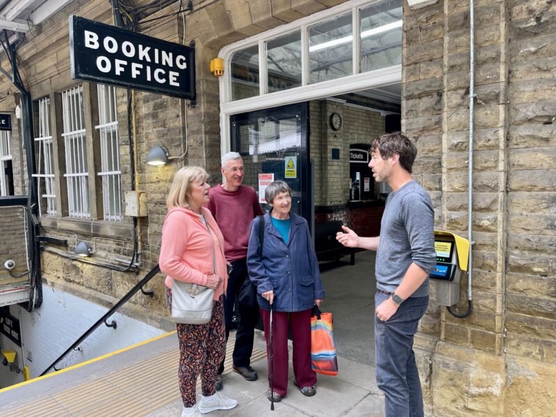 Image shows Councillor Scott Patient speaking to three local residents outside Hebden Bridge station ticket office